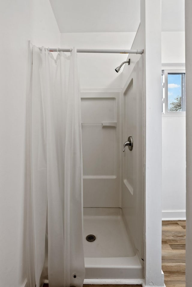 bathroom with a shower stall and wood finished floors