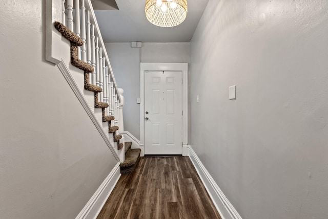 entryway featuring stairway, a notable chandelier, wood finished floors, and baseboards