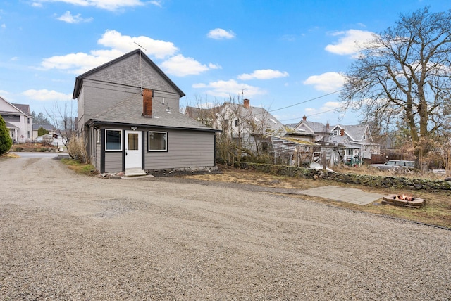 exterior space featuring entry steps, a residential view, driveway, and roof with shingles