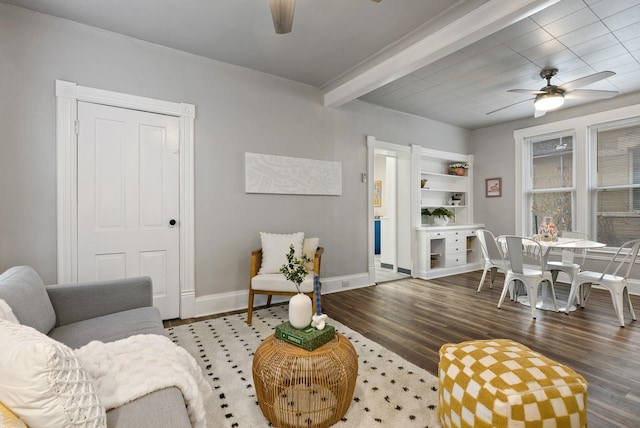 living area featuring beamed ceiling, baseboards, wood finished floors, and a ceiling fan