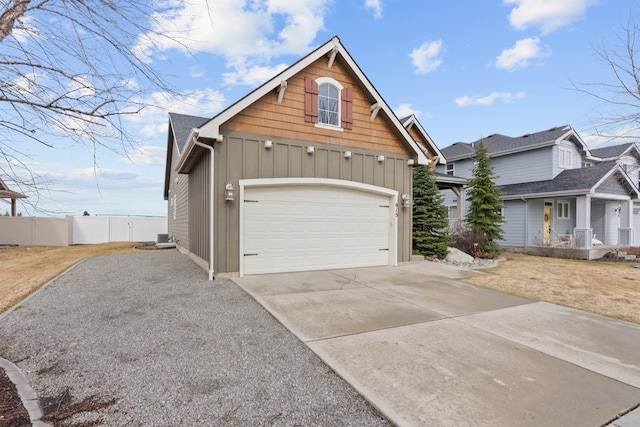 view of front of property featuring board and batten siding, concrete driveway, and fence