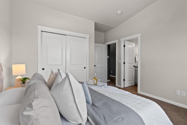 bedroom featuring vaulted ceiling, dark carpet, baseboards, and a closet