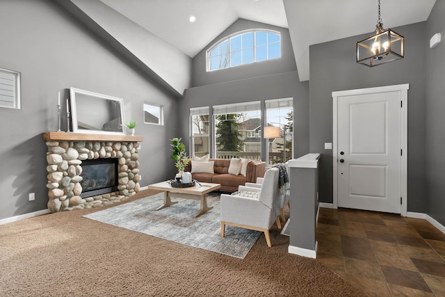 living room with a notable chandelier, a fireplace, baseboards, and high vaulted ceiling