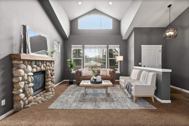 living area with a stone fireplace, high vaulted ceiling, carpet, and baseboards