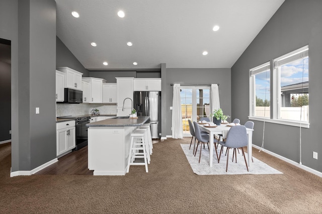 kitchen with white cabinetry, black appliances, an island with sink, and a sink