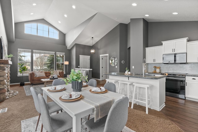 dining space with visible vents, baseboards, high vaulted ceiling, recessed lighting, and dark wood-type flooring