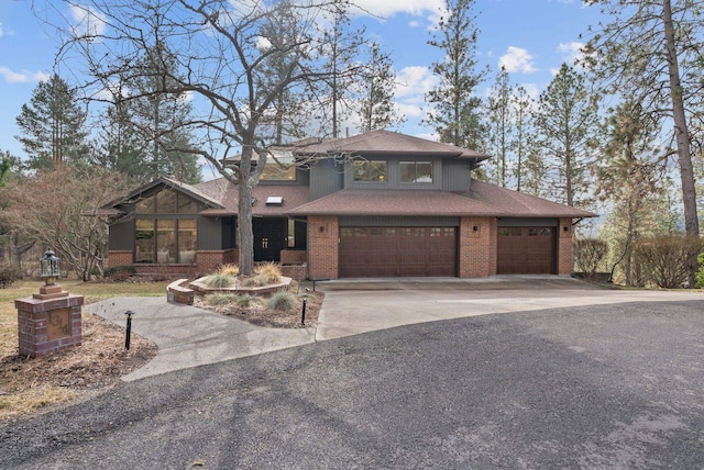 view of front facade with brick siding, driveway, an attached garage, and roof with shingles