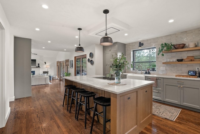 kitchen with dark wood finished floors, light stone countertops, gray cabinets, and a kitchen island