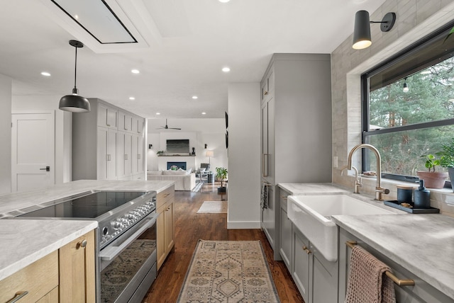 kitchen featuring dark wood-style flooring, gray cabinetry, a sink, stainless steel range with electric stovetop, and open floor plan