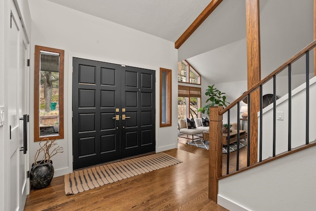 foyer entrance with lofted ceiling with beams, stairway, baseboards, and wood finished floors