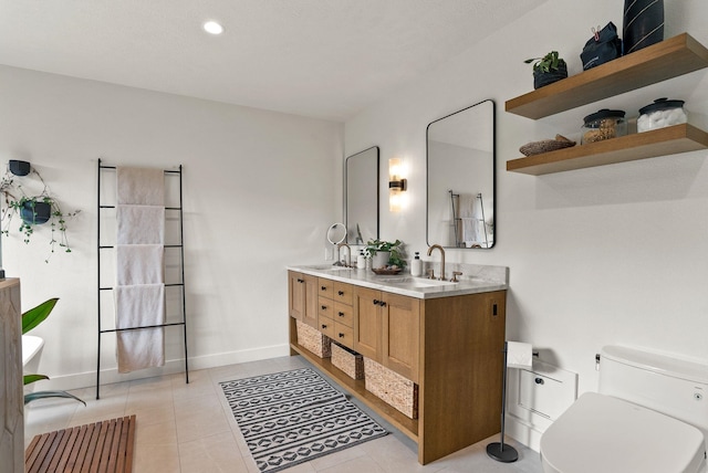 bathroom featuring a sink, toilet, double vanity, and tile patterned floors