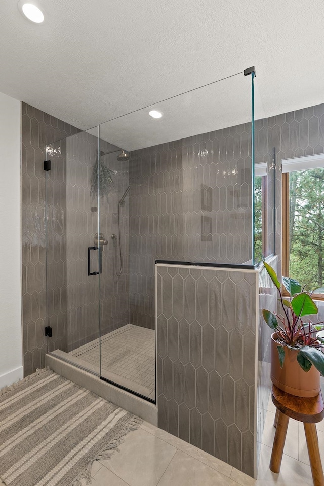 full bath featuring tile patterned flooring, a shower stall, and a textured ceiling