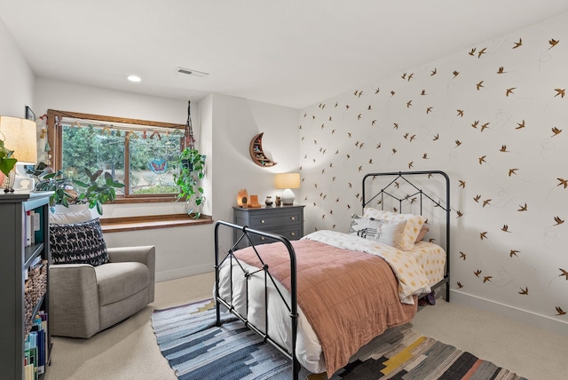 carpeted bedroom featuring visible vents, wallpapered walls, an accent wall, and baseboards