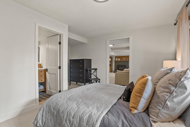 bedroom featuring a fireplace, baseboards, and light carpet