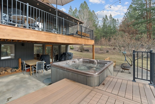 deck with an outdoor fire pit and a hot tub