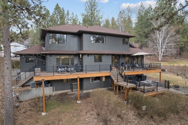 back of house featuring a wooden deck, a shingled roof, and stairway