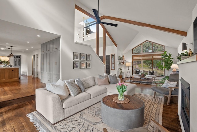 living area with ceiling fan, dark wood finished floors, beamed ceiling, a fireplace, and high vaulted ceiling