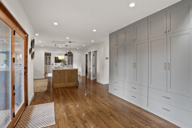 interior space featuring gray cabinetry, open floor plan, a center island, recessed lighting, and dark wood-style flooring