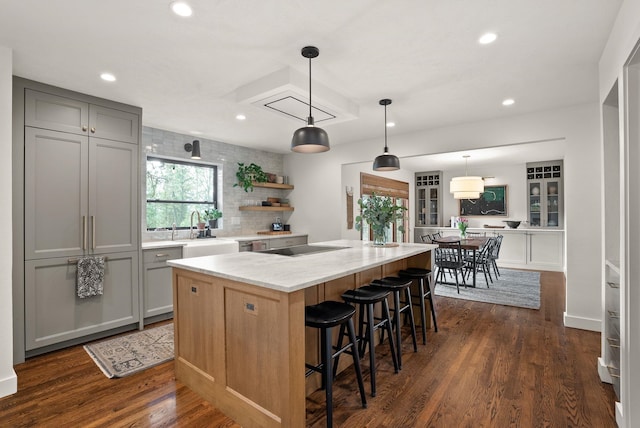 kitchen featuring a breakfast bar area, open shelves, recessed lighting, dark wood-style flooring, and gray cabinetry