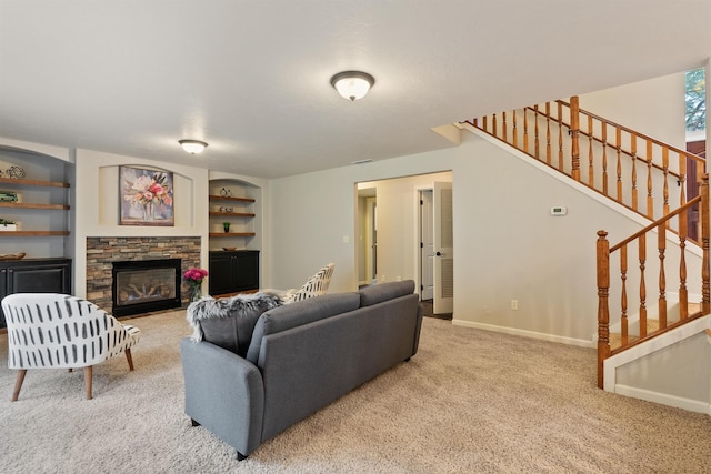 living area featuring built in shelves, baseboards, carpet, stairs, and a stone fireplace