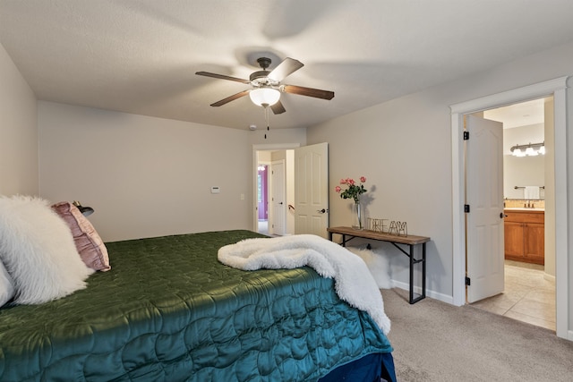 bedroom featuring connected bathroom, light colored carpet, baseboards, and ceiling fan