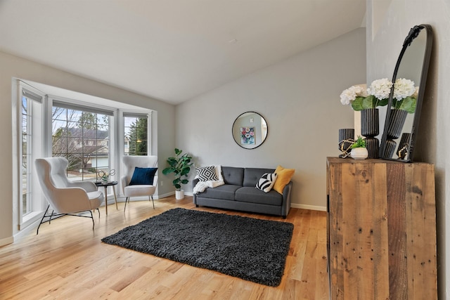 living area featuring wood finished floors, baseboards, and vaulted ceiling