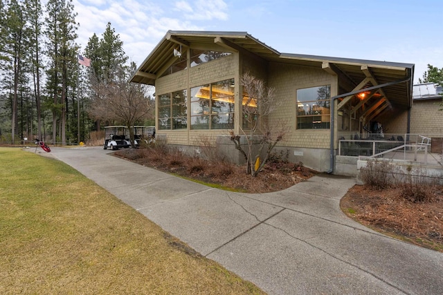 view of side of property with a sunroom, a lawn, driveway, and crawl space