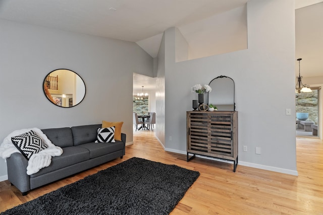 living area featuring baseboards, lofted ceiling, an inviting chandelier, and wood finished floors