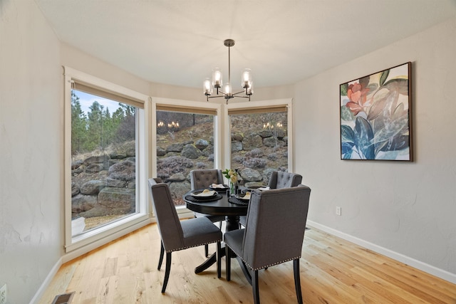 dining area featuring visible vents, baseboards, an inviting chandelier, and wood finished floors