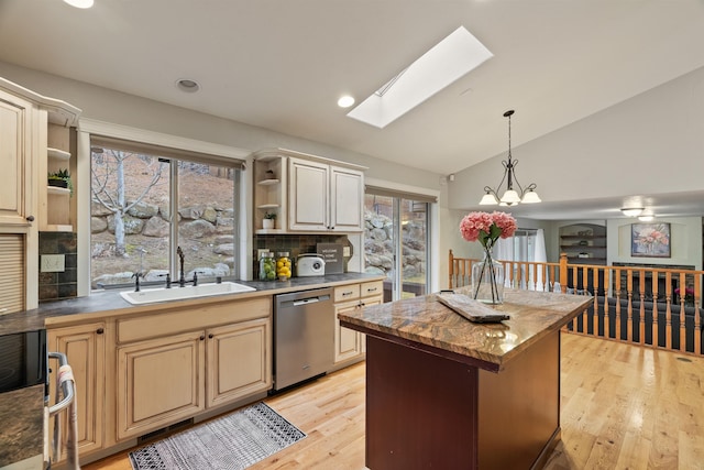 kitchen featuring open shelves, lofted ceiling with skylight, an inviting chandelier, stainless steel appliances, and a sink