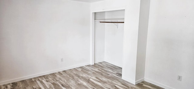 unfurnished bedroom with wood finished floors, a closet, and baseboards