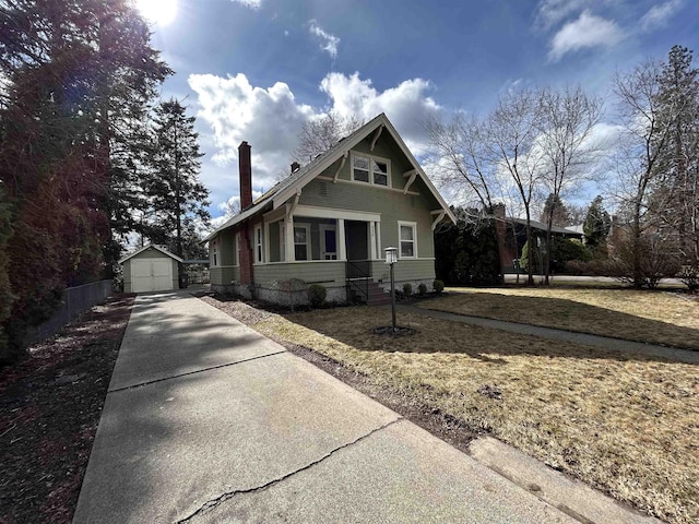 view of front of house with an outbuilding, driveway, a front lawn, and fence