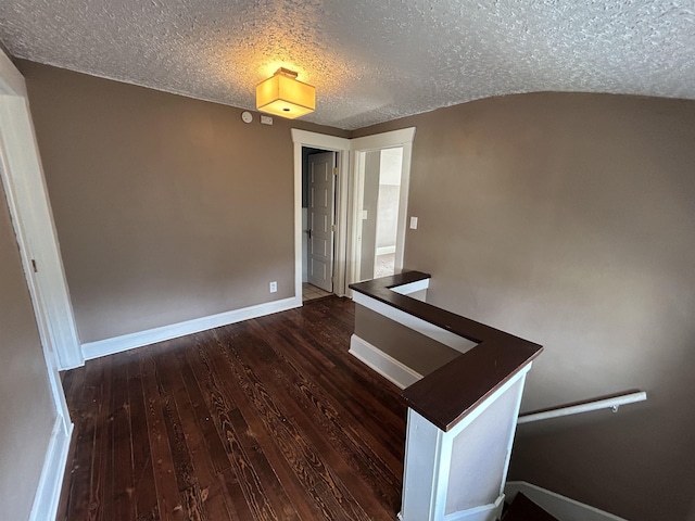 interior space featuring a textured ceiling, baseboards, and wood finished floors