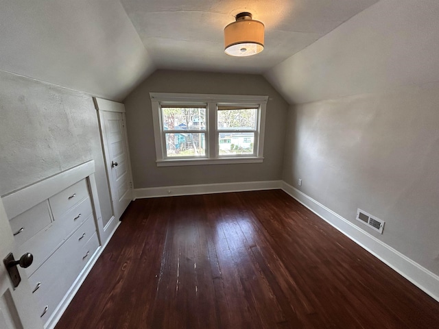 bonus room with hardwood / wood-style floors, lofted ceiling, baseboards, and visible vents