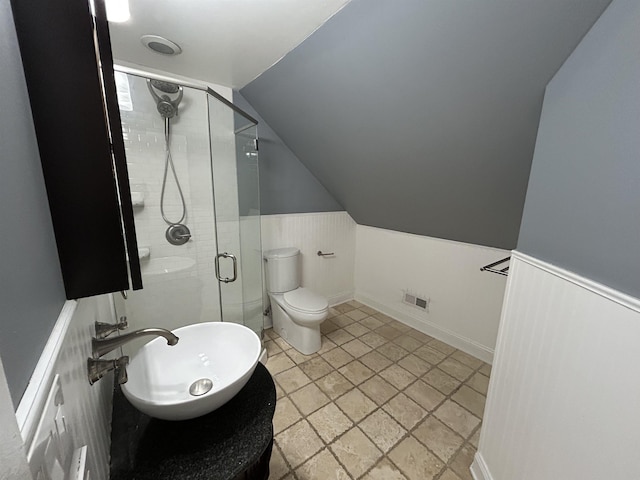 full bathroom featuring visible vents, a stall shower, vaulted ceiling, wainscoting, and toilet