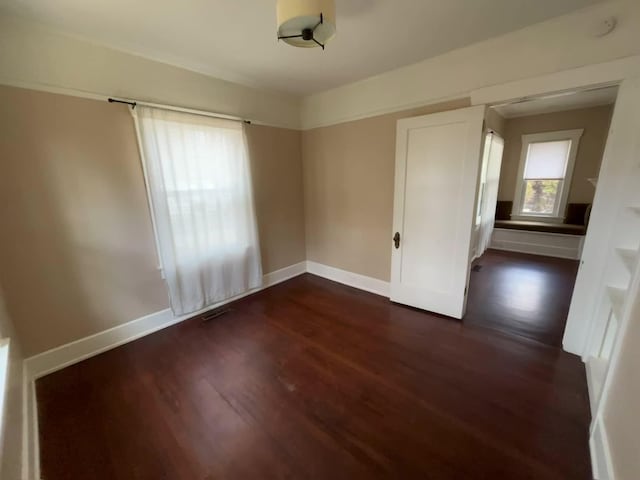 spare room featuring visible vents, baseboards, and wood finished floors