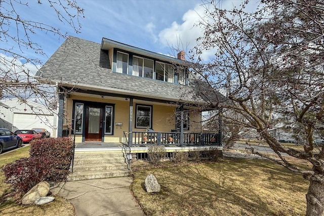 view of front of house with roof with shingles, a front yard, covered porch, a chimney, and a garage