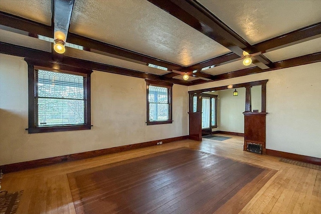 unfurnished room featuring beam ceiling, coffered ceiling, a textured ceiling, wood-type flooring, and baseboards