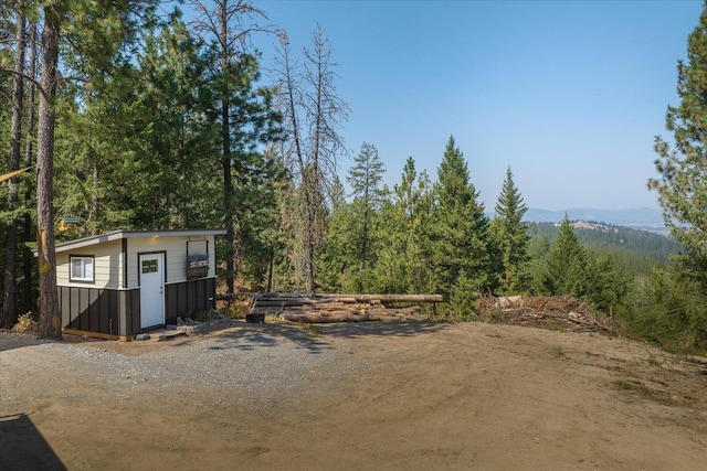 exterior space with a shed, a forest view, and an outdoor structure