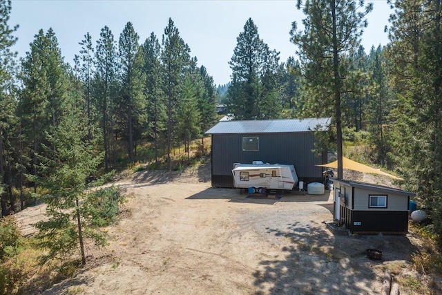 view of front of house with a view of trees and an outbuilding