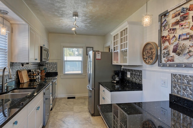 kitchen with decorative backsplash, white cabinets, appliances with stainless steel finishes, and a sink