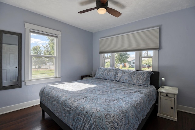 bedroom with dark wood finished floors, a ceiling fan, and baseboards