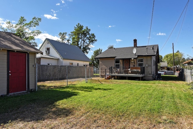 rear view of house with a yard, a fenced backyard, a chimney, an outdoor structure, and a deck