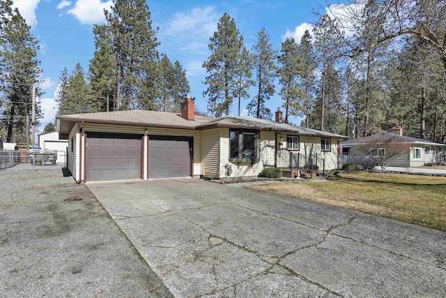 single story home featuring a front yard, an attached garage, driveway, and a chimney