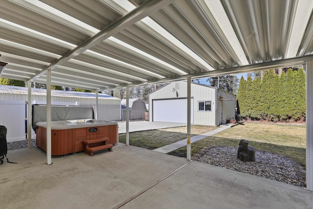 view of patio with a garage, a hot tub, an outdoor structure, and fence