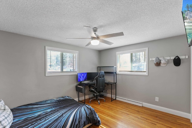 bedroom with ceiling fan, a baseboard radiator, baseboards, and wood finished floors