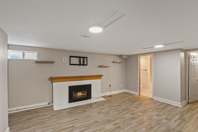 unfurnished living room with a brick fireplace, baseboards, and wood finished floors