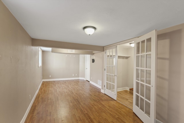 finished basement with wood finished floors, french doors, visible vents, and baseboards