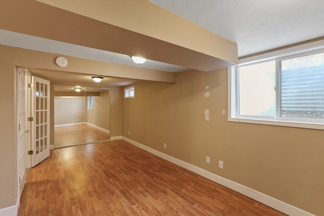 basement with a wealth of natural light, baseboards, and wood finished floors