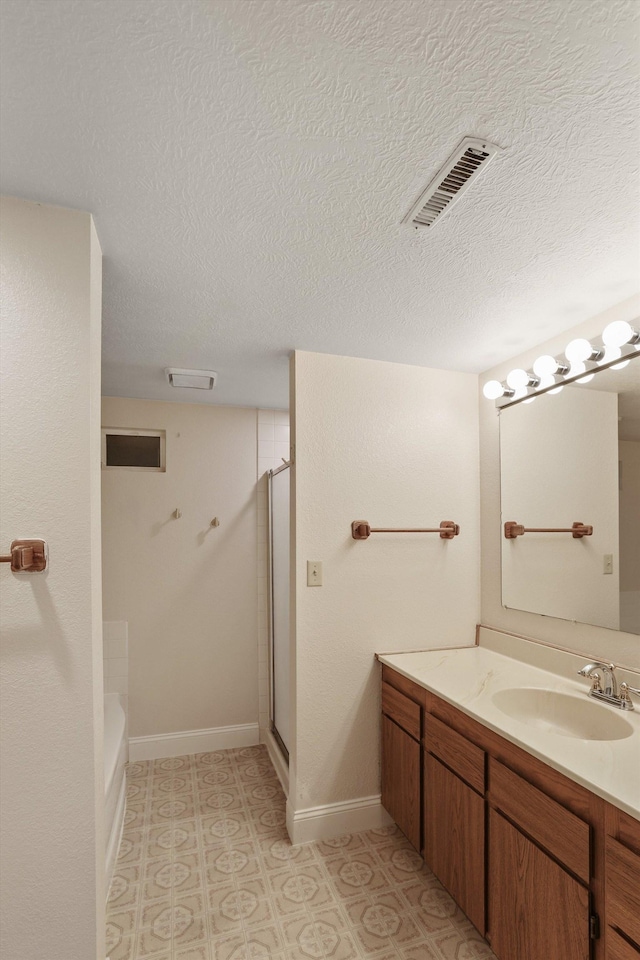 bathroom with vanity, baseboards, visible vents, walk in shower, and a textured ceiling